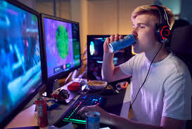 A young male gamer drinking an energy drink while playing a video game in a dark room