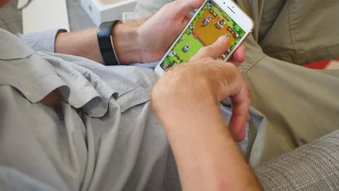 A man playing the mobile game Clash Royale on a smartphone